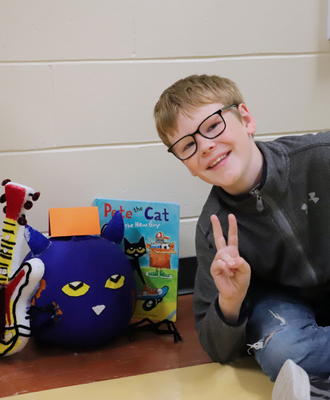  Photo of male student with his "Pete the Cat" book and decorated pumpkin.